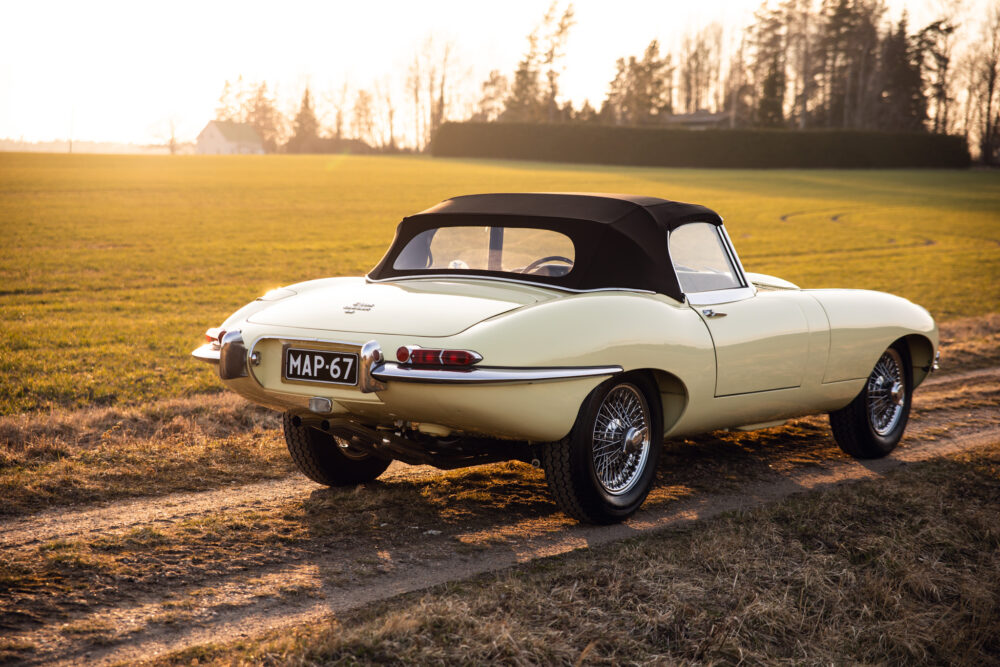 Vintage beige convertible car in open field at sunset