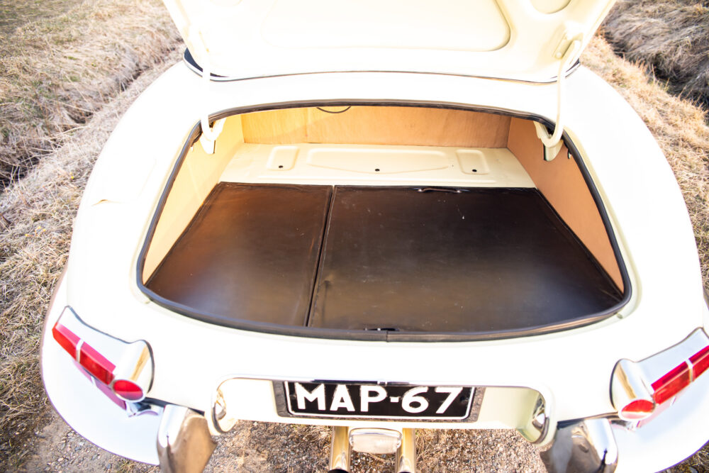 Open trunk of a vintage white car displaying interior