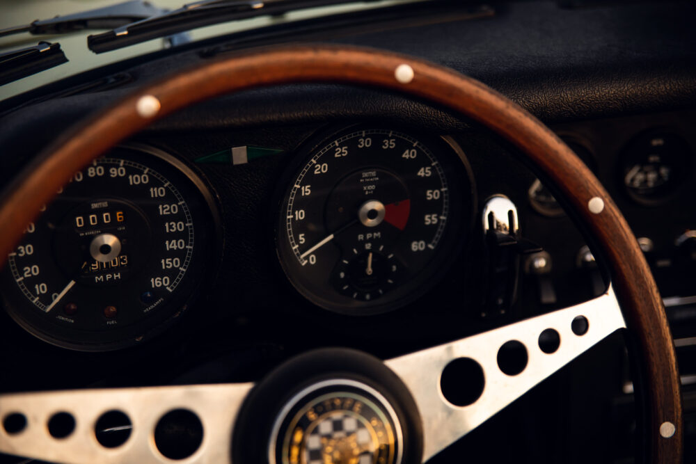 Vintage car dashboard with speedometer and wooden steering wheel