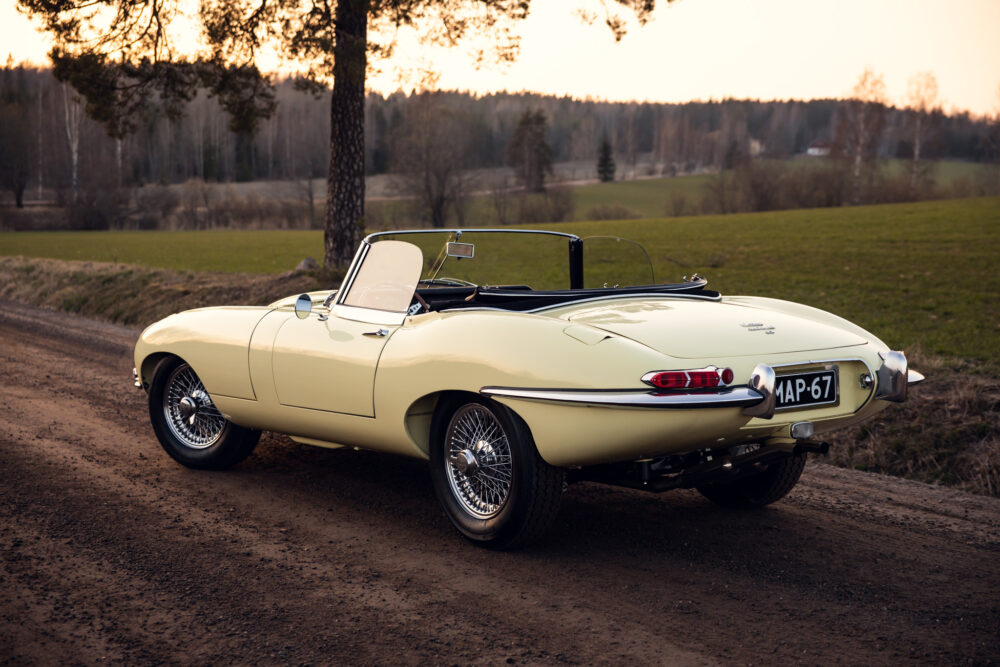 Vintage yellow convertible car parked near a wooded area