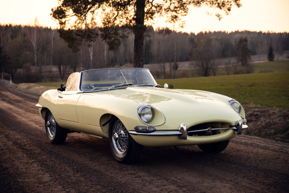 Vintage yellow Jaguar E-Type convertible on rural road