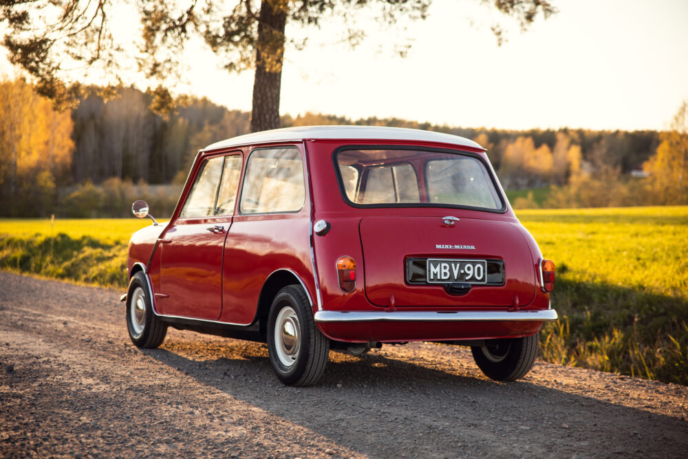 Vintage red Mini Minor car on countryside road at sunset