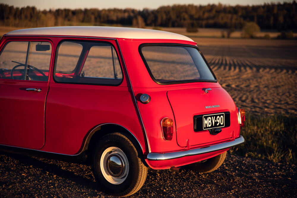 Red vintage Mini Minor car in golden hour field