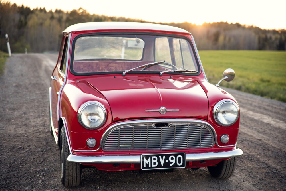 Vintage red Mini Cooper on countryside road at sunset