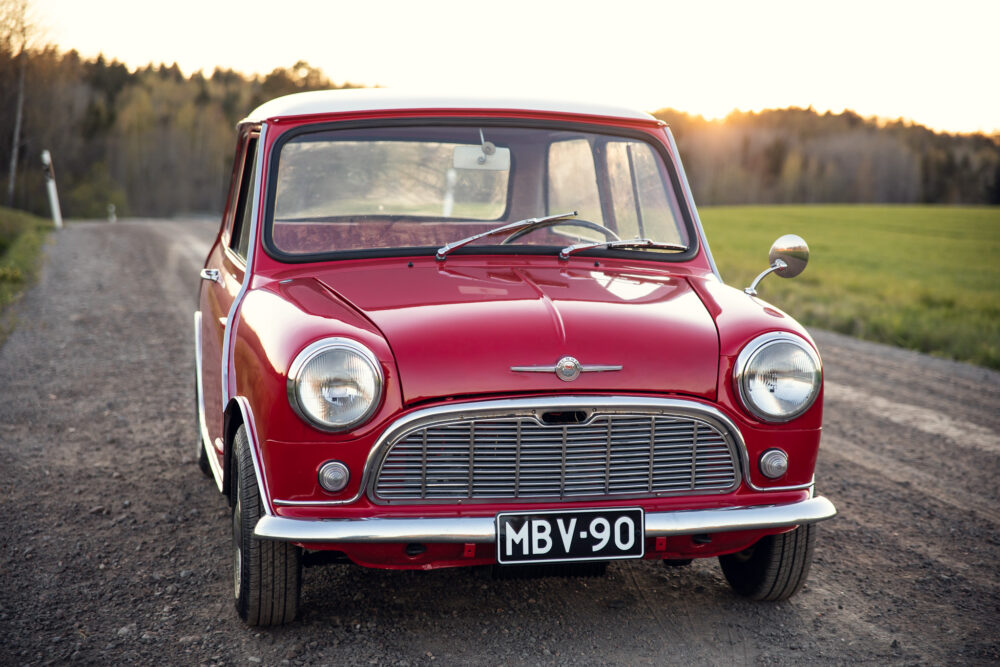 Vintage red Mini Cooper on a country road at sunset