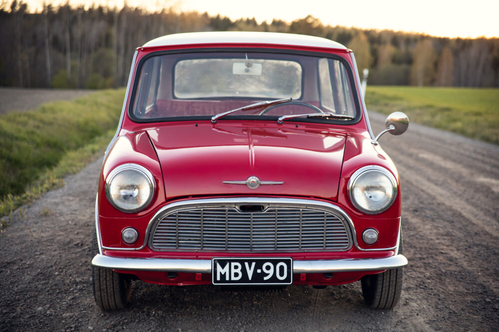 Red vintage Mini Cooper on countryside road at dusk