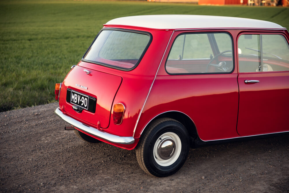 Vintage red Mini Cooper on green grass at sunset