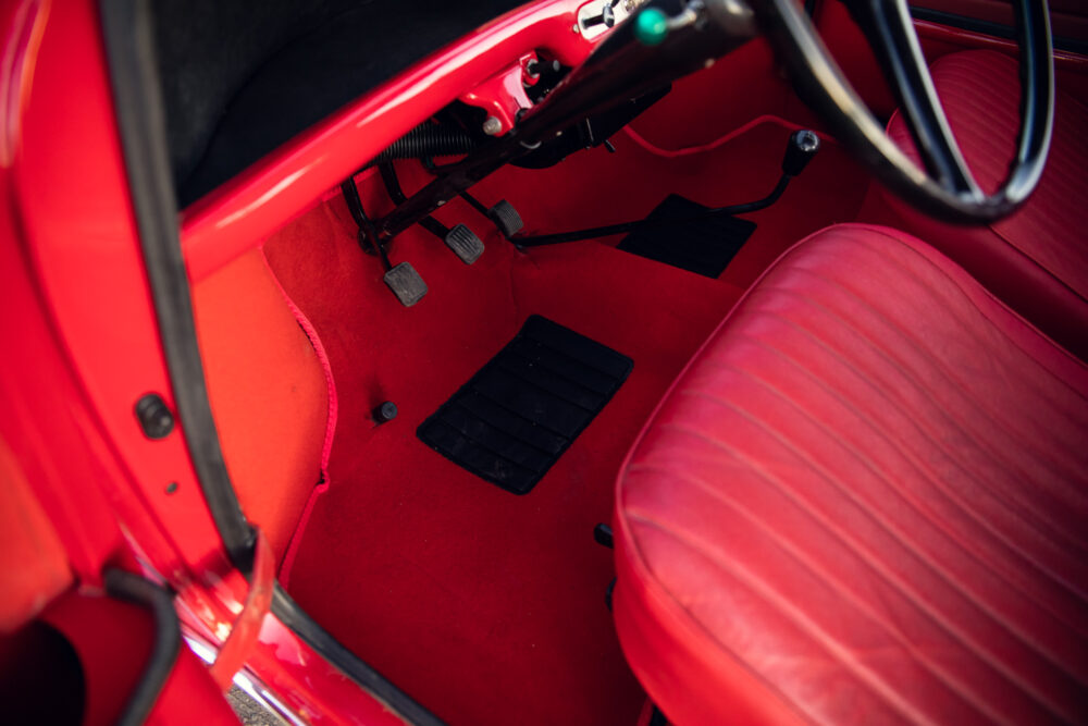 Vintage red car interior with red seats and pedals