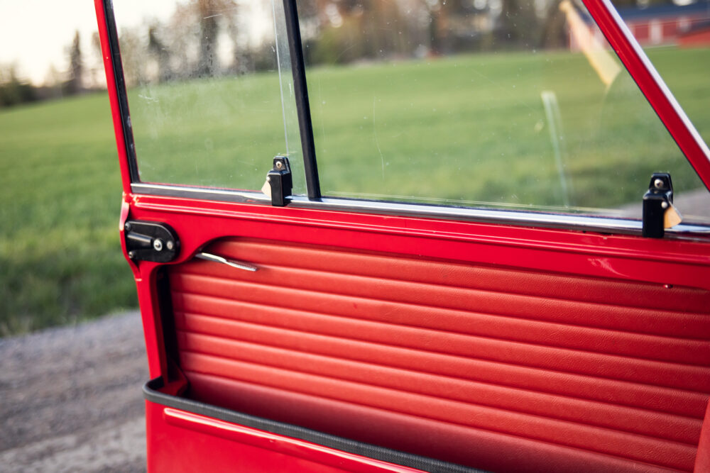 Close-up of red car door with countryside backdrop
