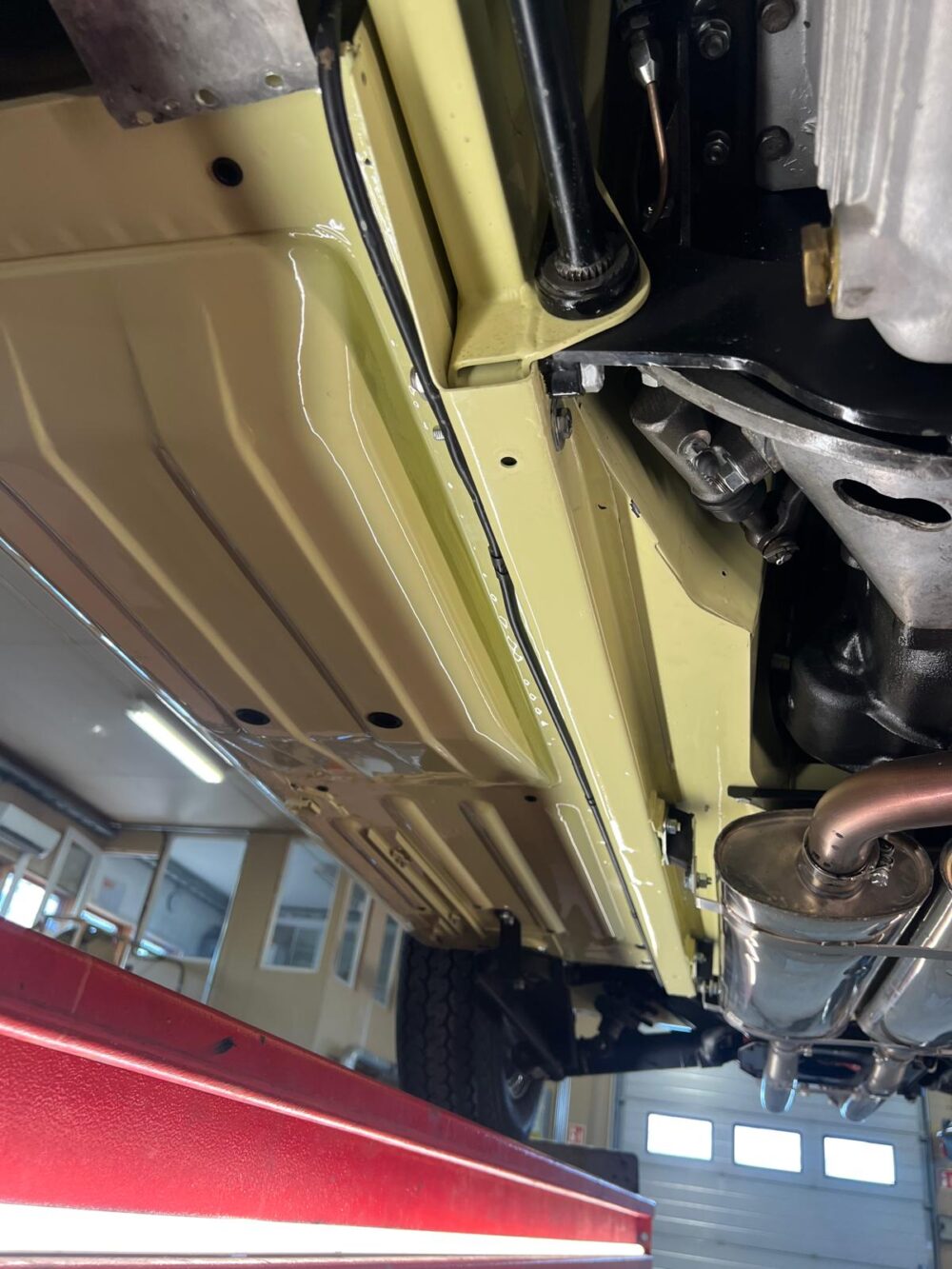Underside of a yellow car on a lift in garage