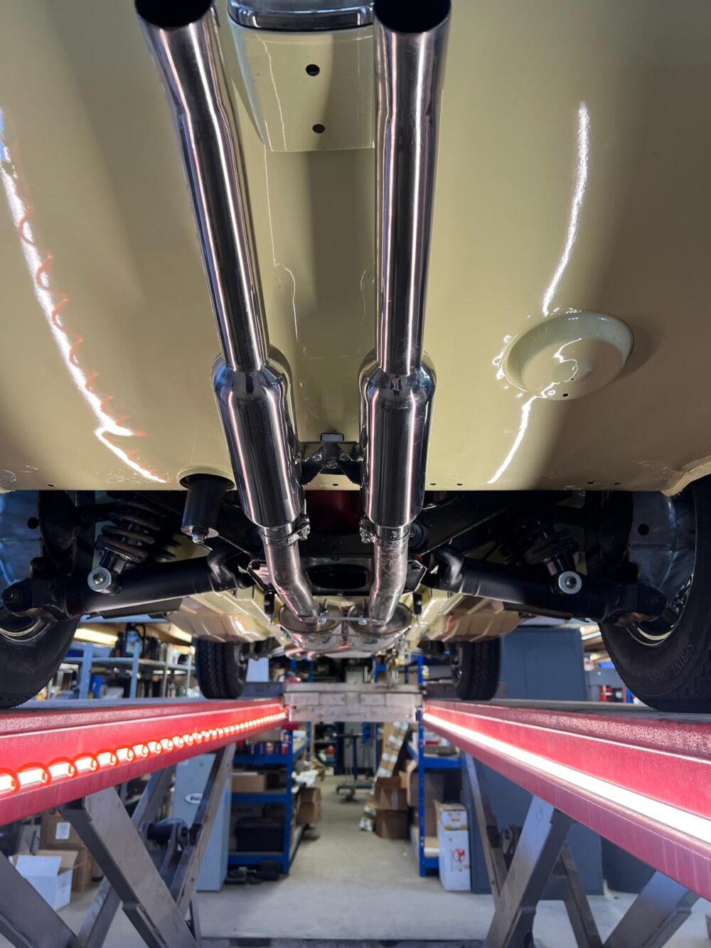 Undercarriage view of a vintage yellow car in workshop