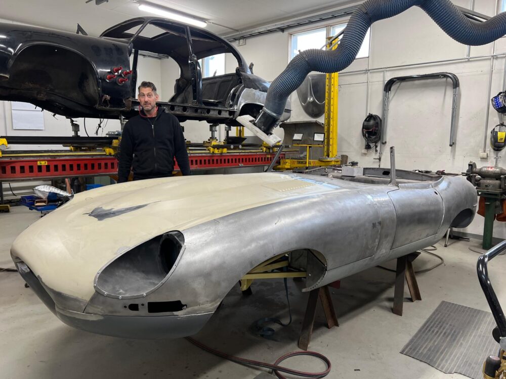 Man standing by vintage car undergoing restoration