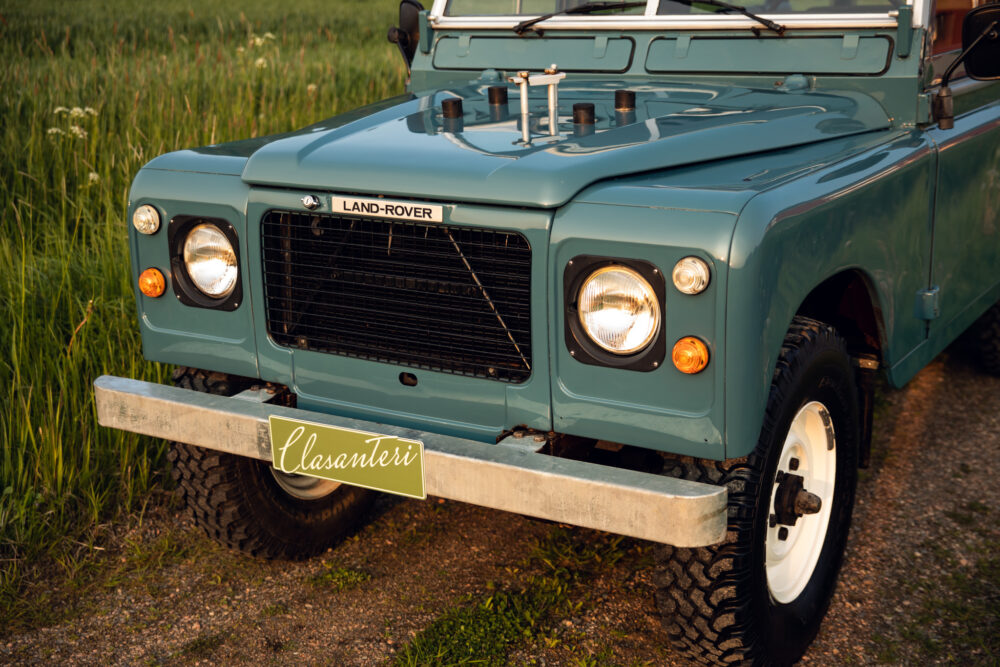 Vintage teal Land Rover on a grassy field