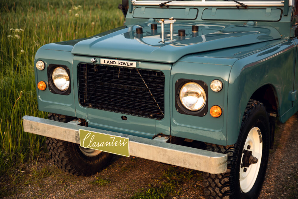 Vintage turquoise Land Rover on grassy field