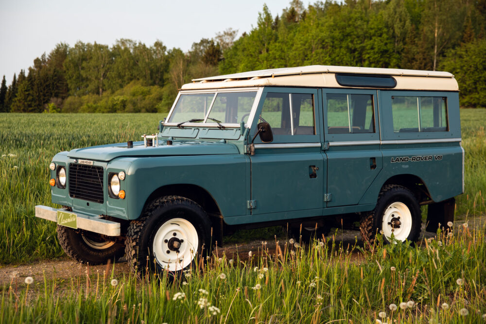 Vintage blue Land Rover parked in green field