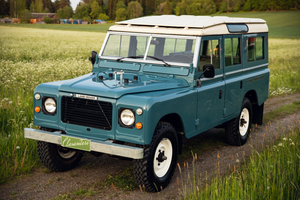 Vintage blue Land Rover in lush green field