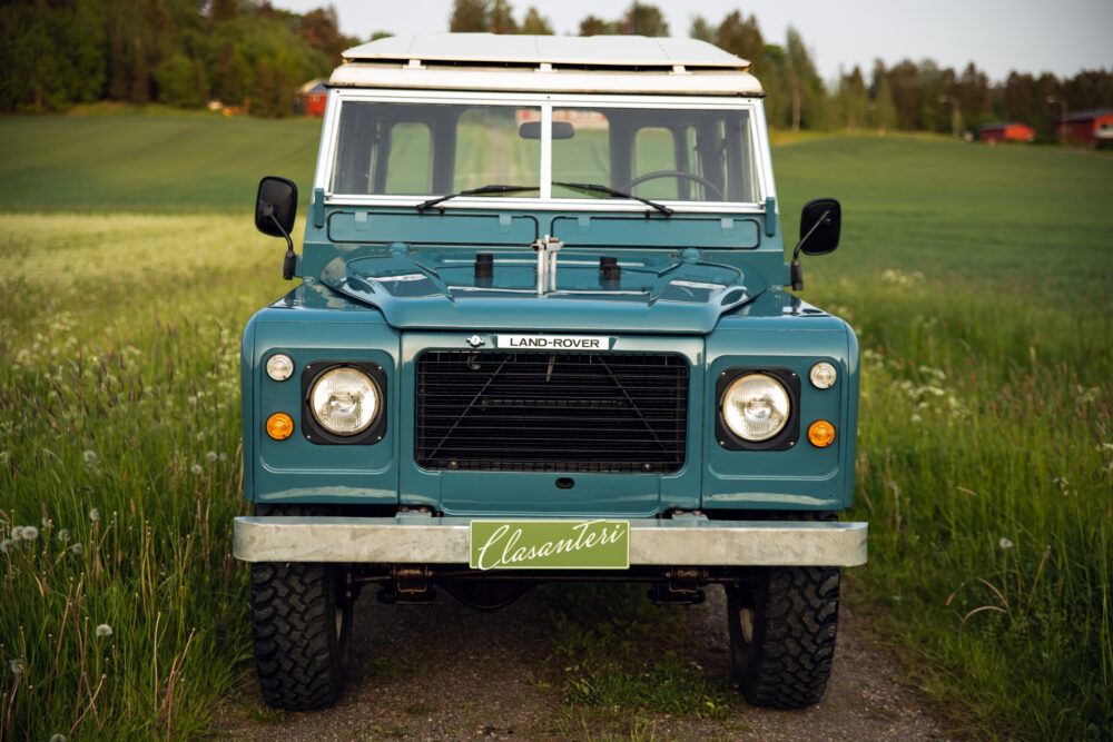 Vintage blue Land Rover on a lush green field