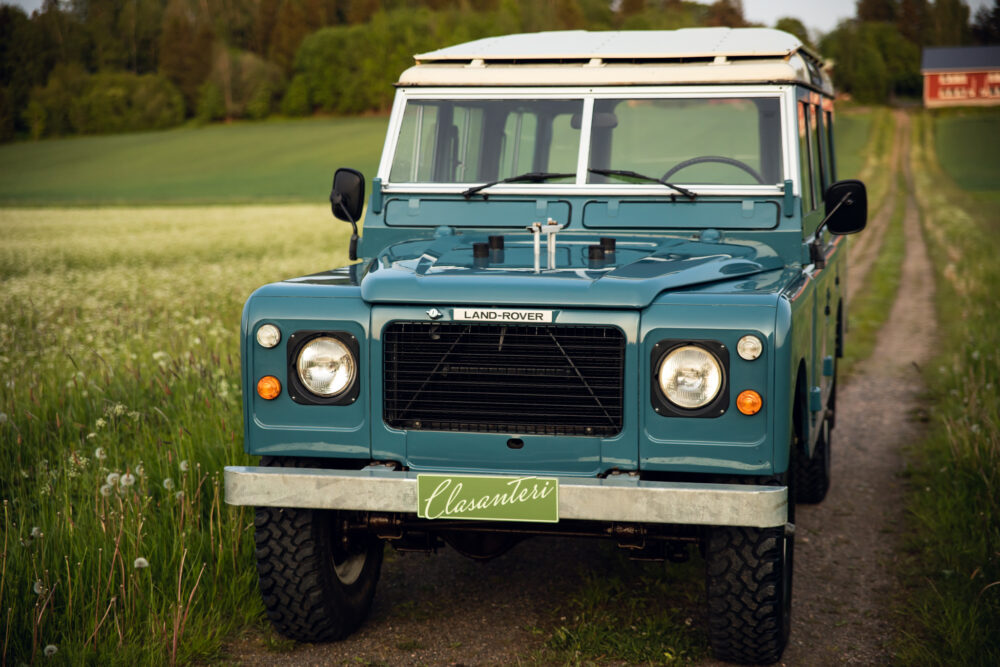 Vintage blue Land Rover on rural path at dusk