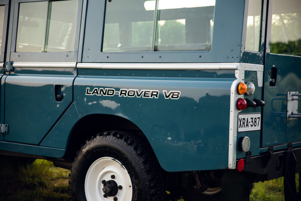 Close-up of teal Land-Rover V8 side and license plate