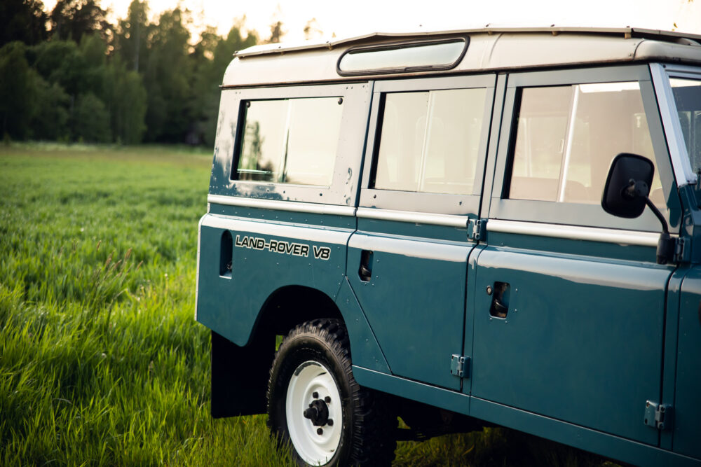 Blue Land Rover V8 parked in a lush field