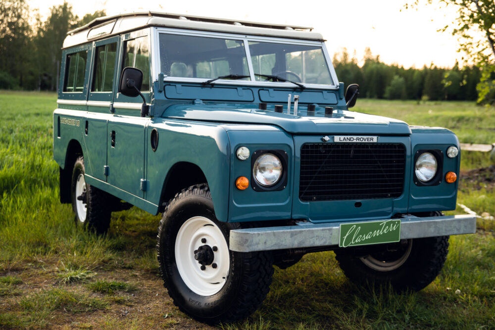 Vintage blue Land Rover parked in grassy field