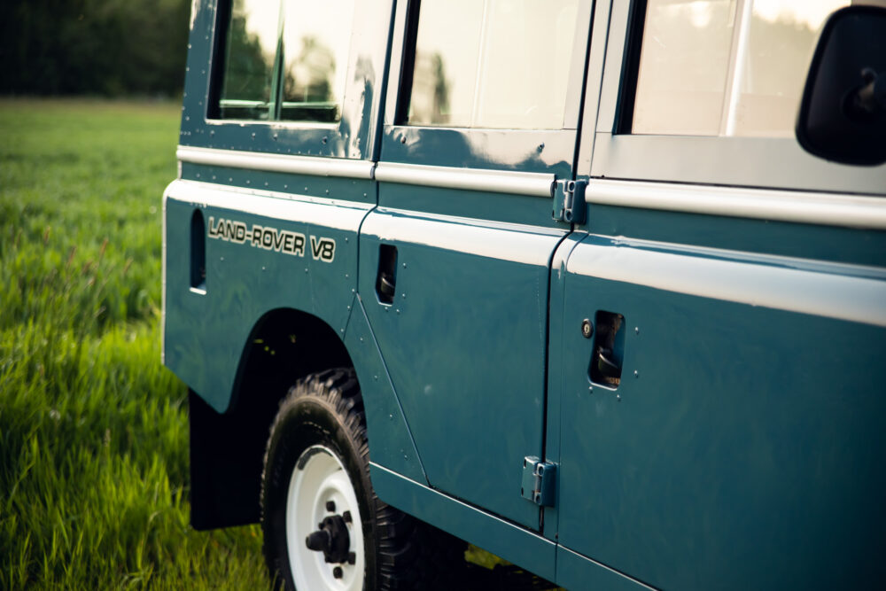 Blue Land Rover V8 parked in a grassy field