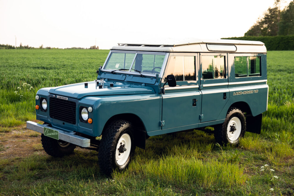 Blue Land Rover Defender in green field at dusk