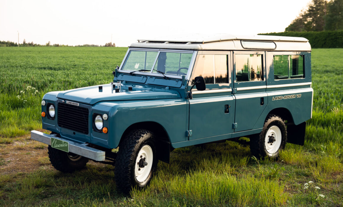 Blue Land Rover Defender in green field at dusk