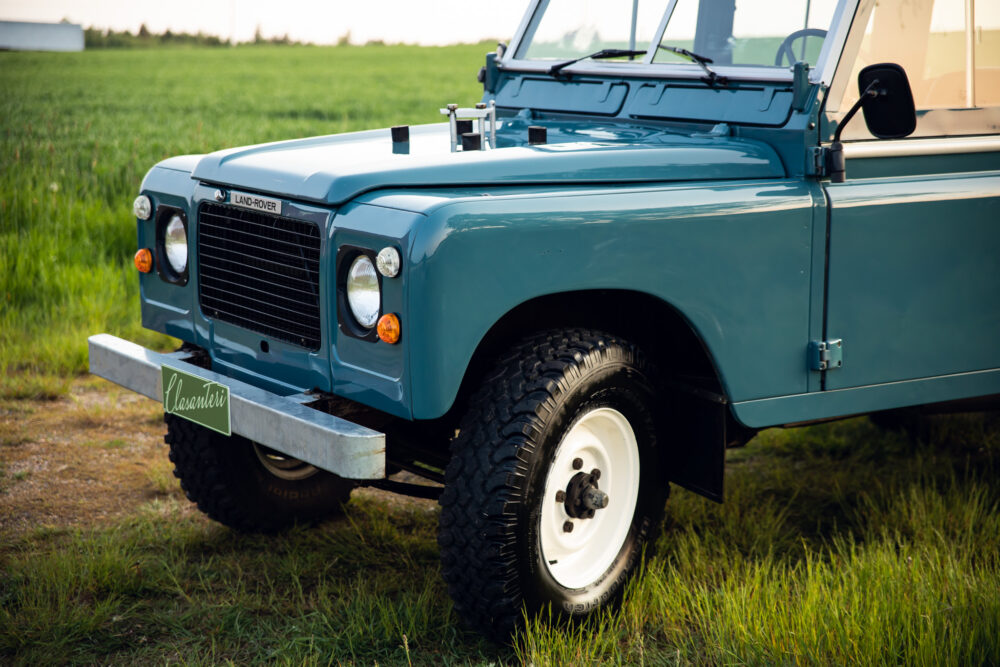 Vintage blue Land Rover parked in grassy field
