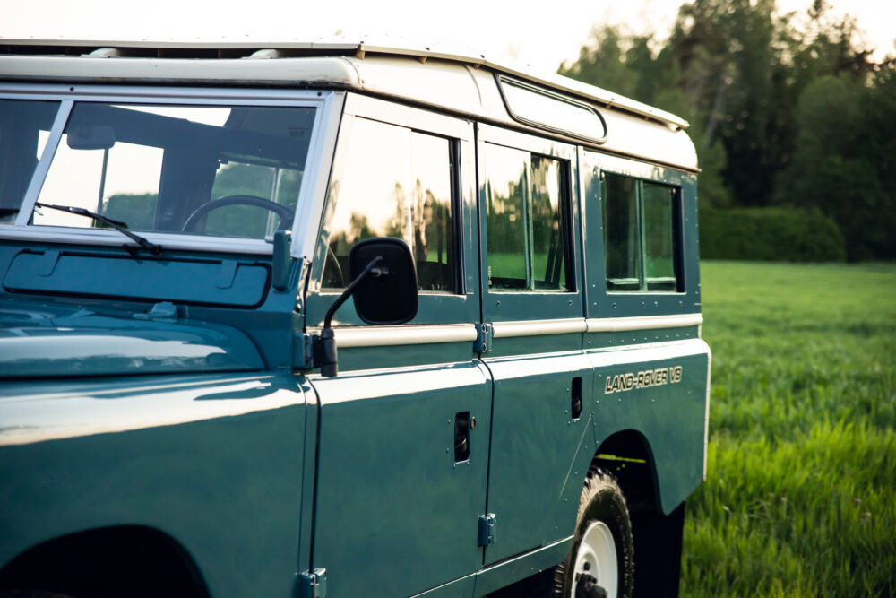 Vintage blue Land Rover in a green field at dusk