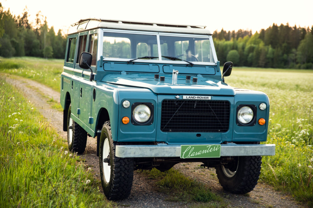 Vintage blue Land Rover in lush green field