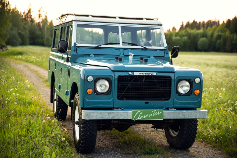 Vintage blue Land Rover on country road at sunset