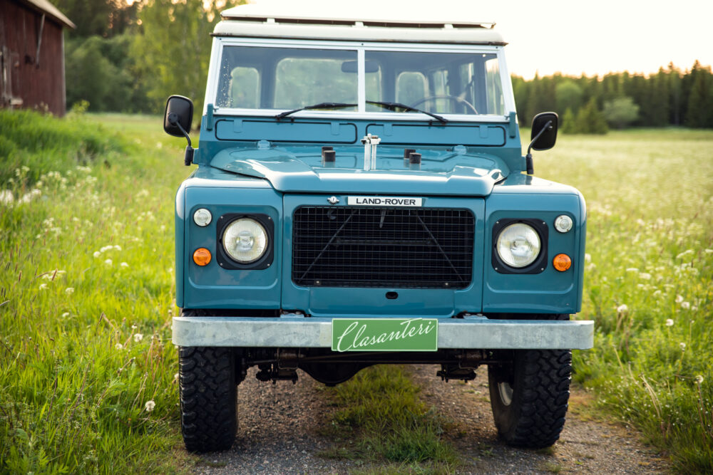 Vintage Land Rover in grassy field at dusk
