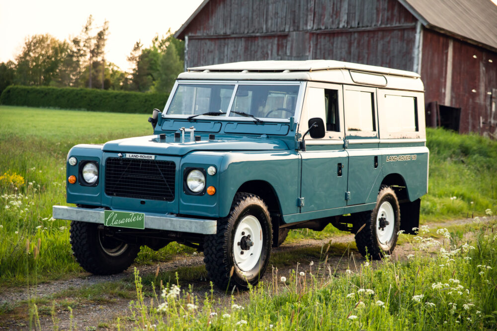 Vintage blue Land Rover parked near rustic barn