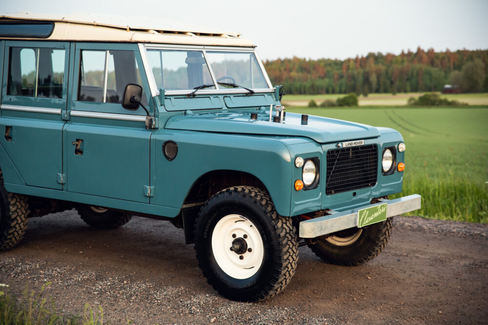 Vintage teal Land Rover on rural gravel road