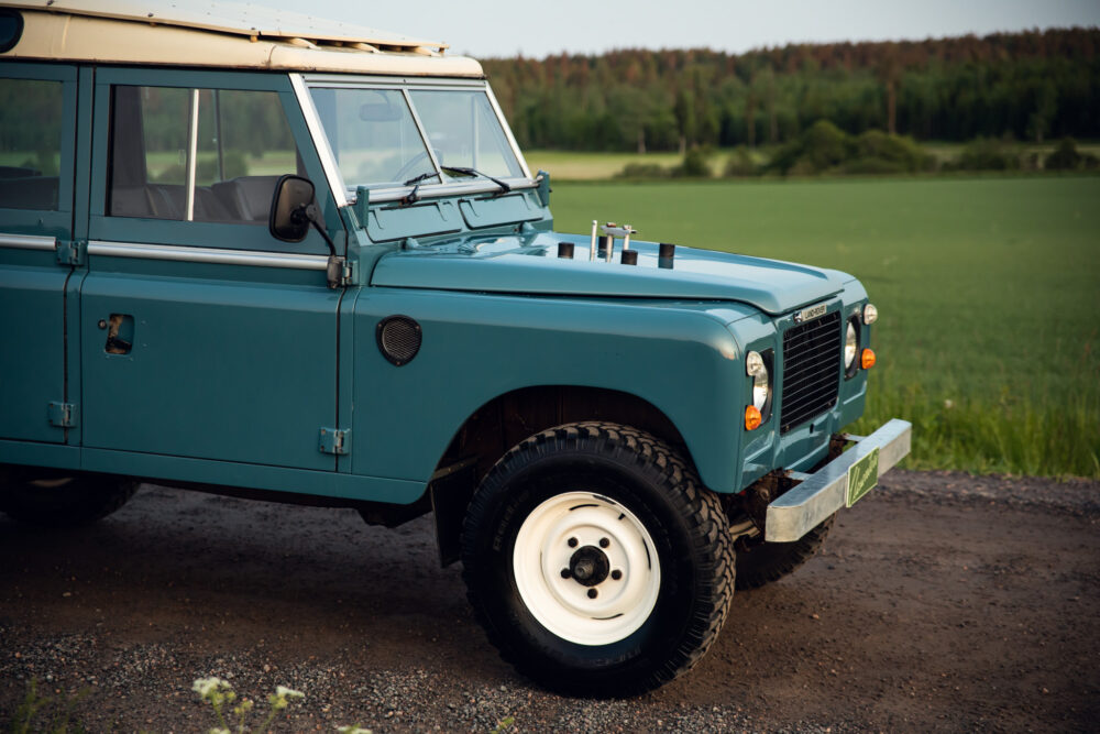 Vintage blue Land Rover in lush green field
