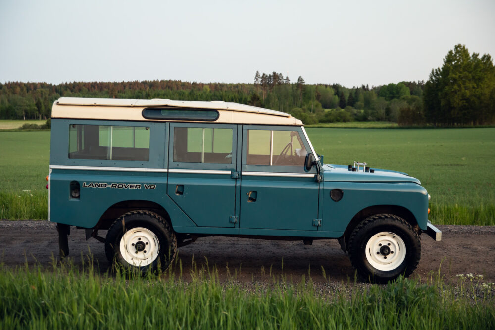 Vintage blue Land Rover on rural road at dusk