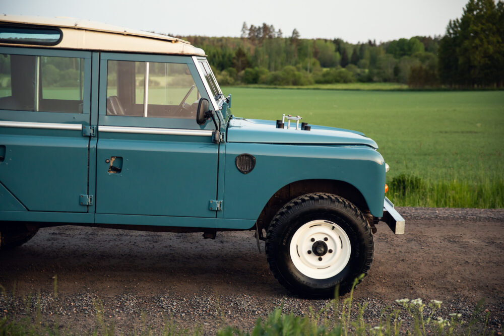 Vintage blue SUV parked near green field