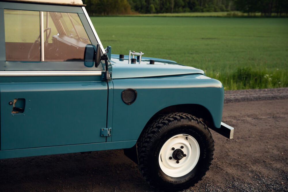 Vintage blue off-road vehicle parked beside green field
