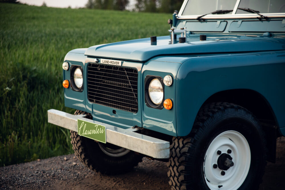 Vintage Land Rover parked in lush green field