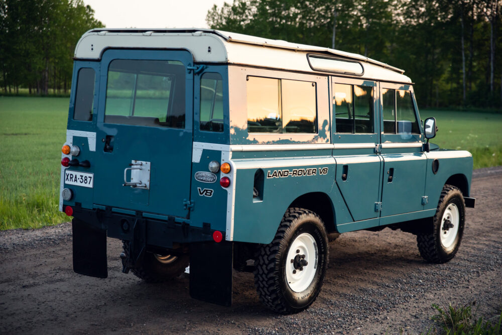 Vintage Land Rover V8 on a dirt road at sunset
