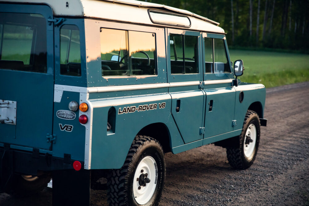 Vintage blue Land Rover V8 on forest road at dusk