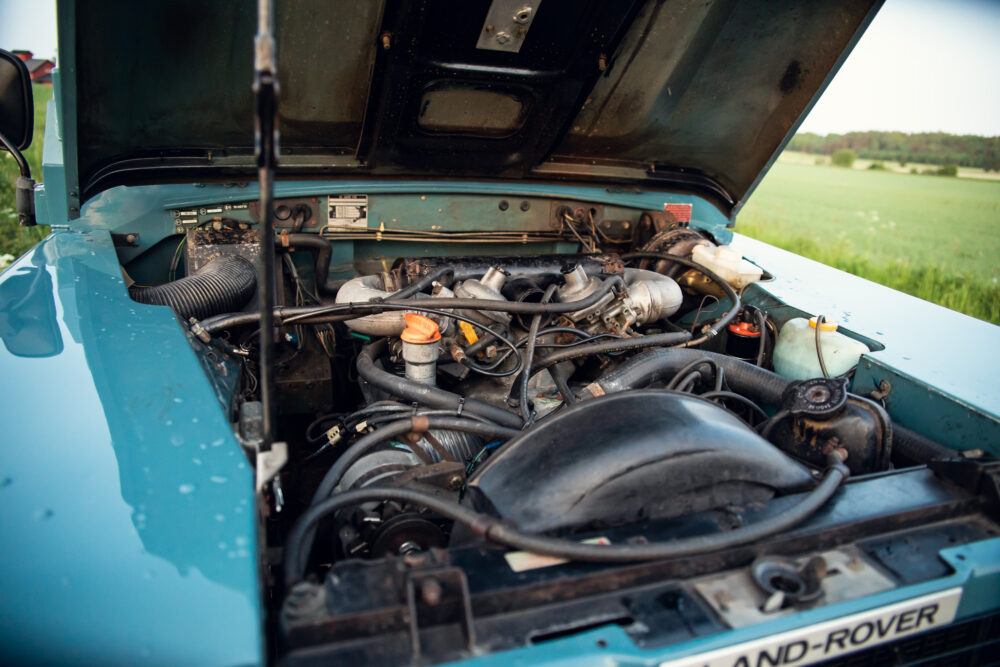 Open hood of a vintage Land Rover engine in field