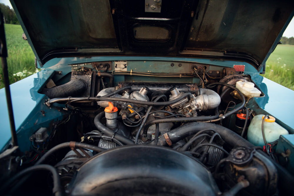 Vintage car engine bay open in field