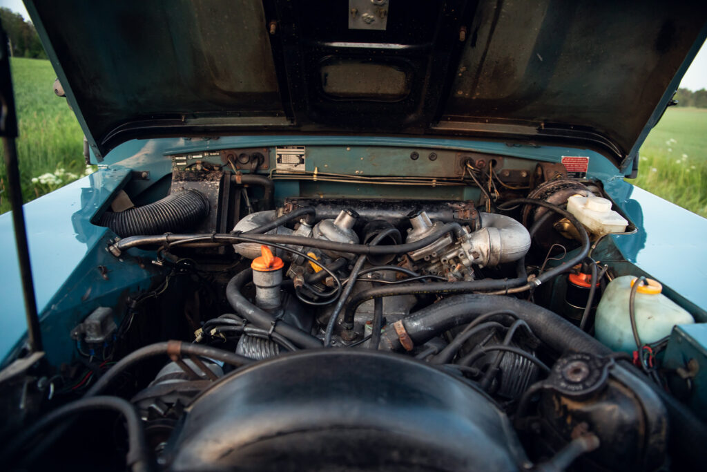 Vintage car engine bay open in field