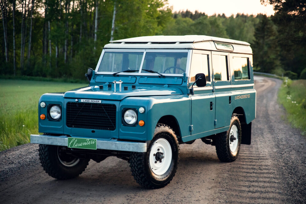 Vintage blue Land Rover on forest road at dusk