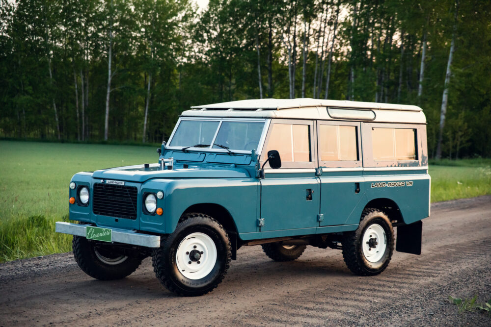Vintage blue Land Rover on rural forest road