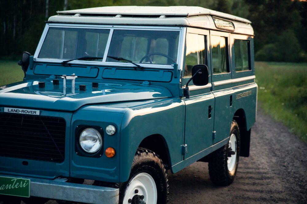 Vintage blue Land Rover on rural road at dusk