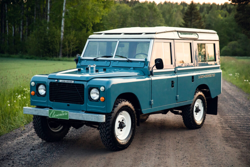 Vintage blue Land Rover on rural road at dusk