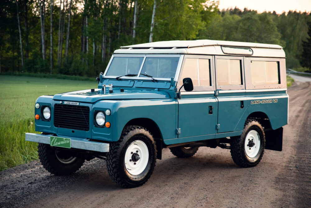 Vintage blue Land Rover on a forest road at dusk